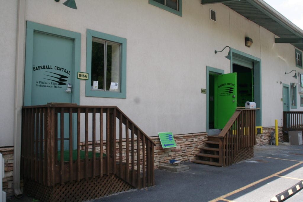 A green door and wooden steps leading to the front of a building.