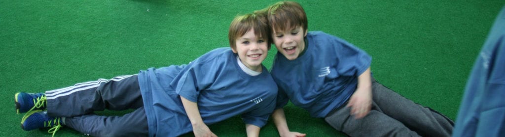 Two boys in blue shirts are laying on the ground.