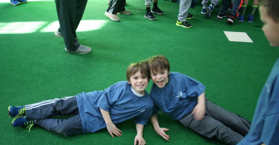 Two boys laying on the ground in front of a crowd.