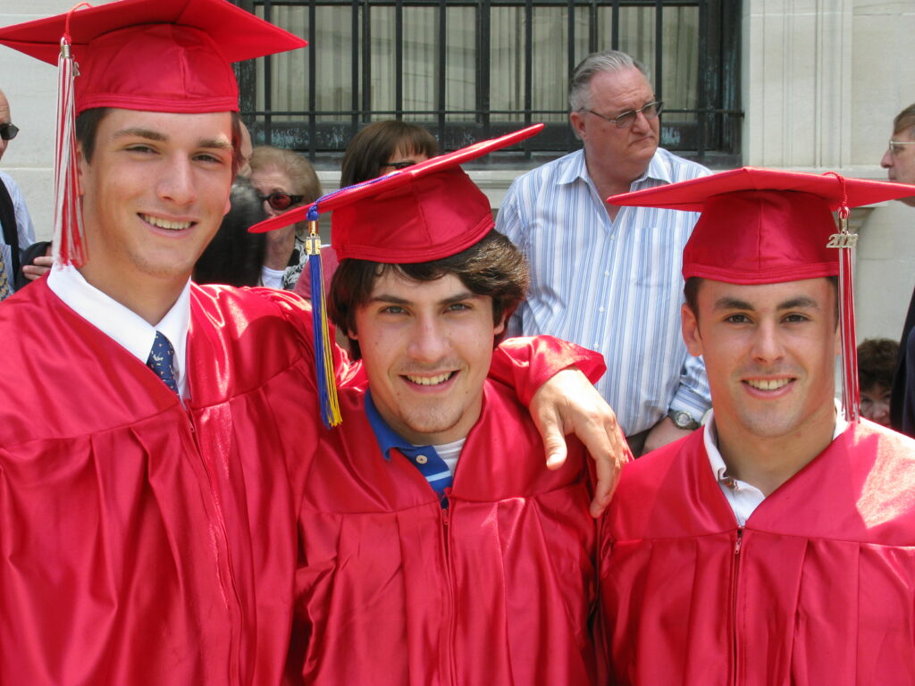Three young men in red graduation caps and gowns.