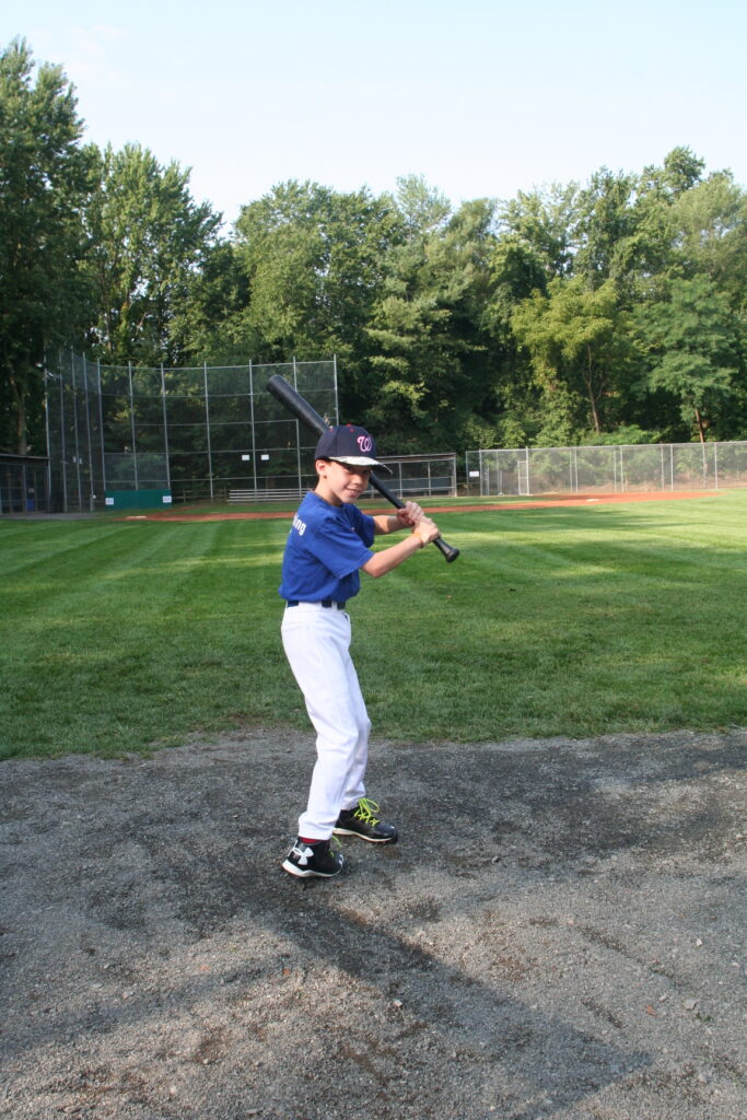A young man holding a baseball bat on top of a field.