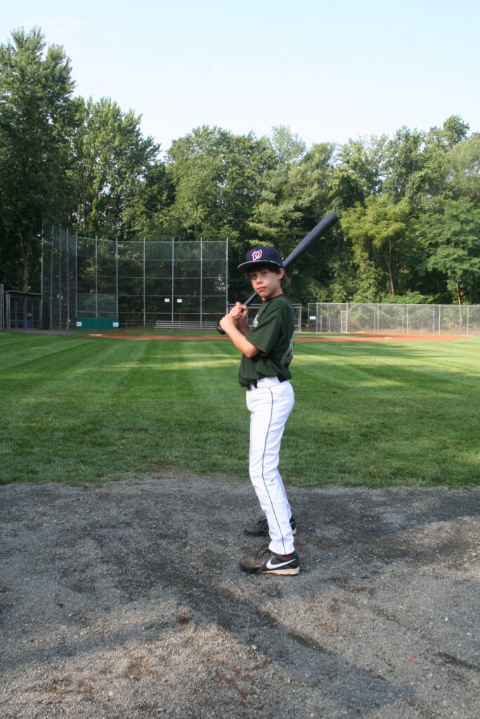 A baseball player is holding his bat on the field.