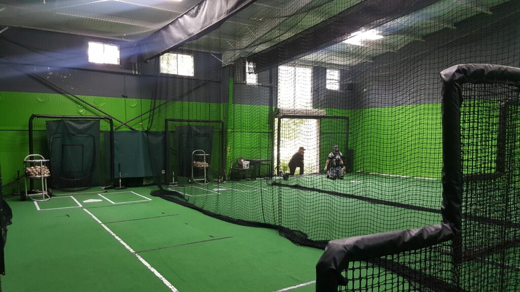 A large indoor batting cage with green walls.