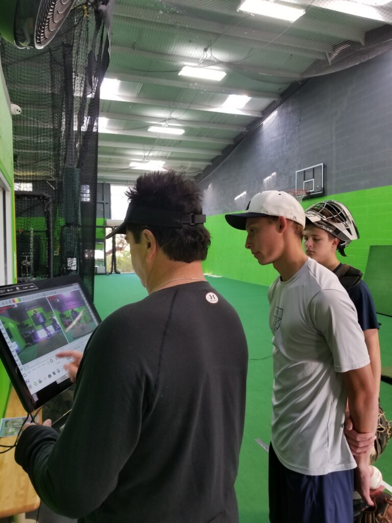 Three men are standing in a room looking at a computer.