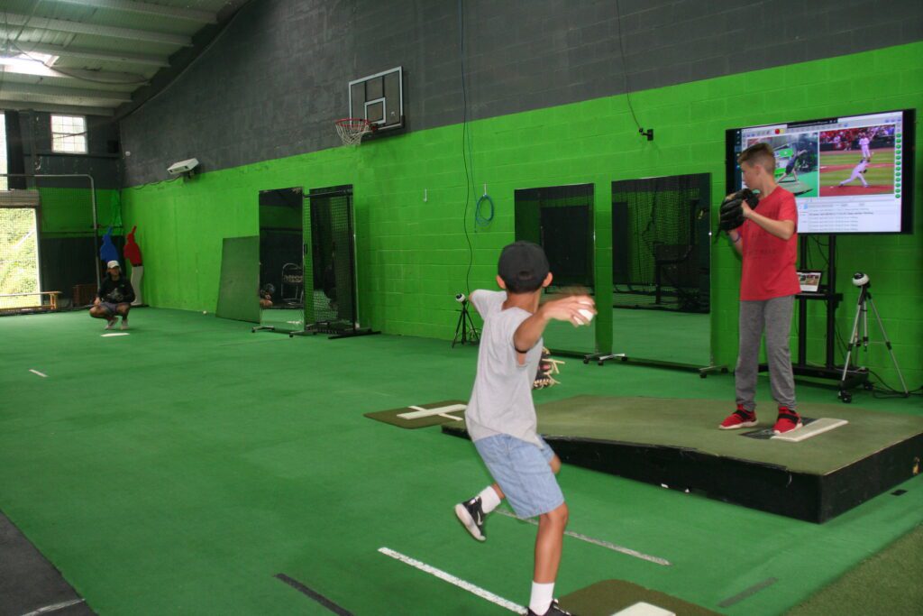 A boy is swinging at a ball in the batting cage.