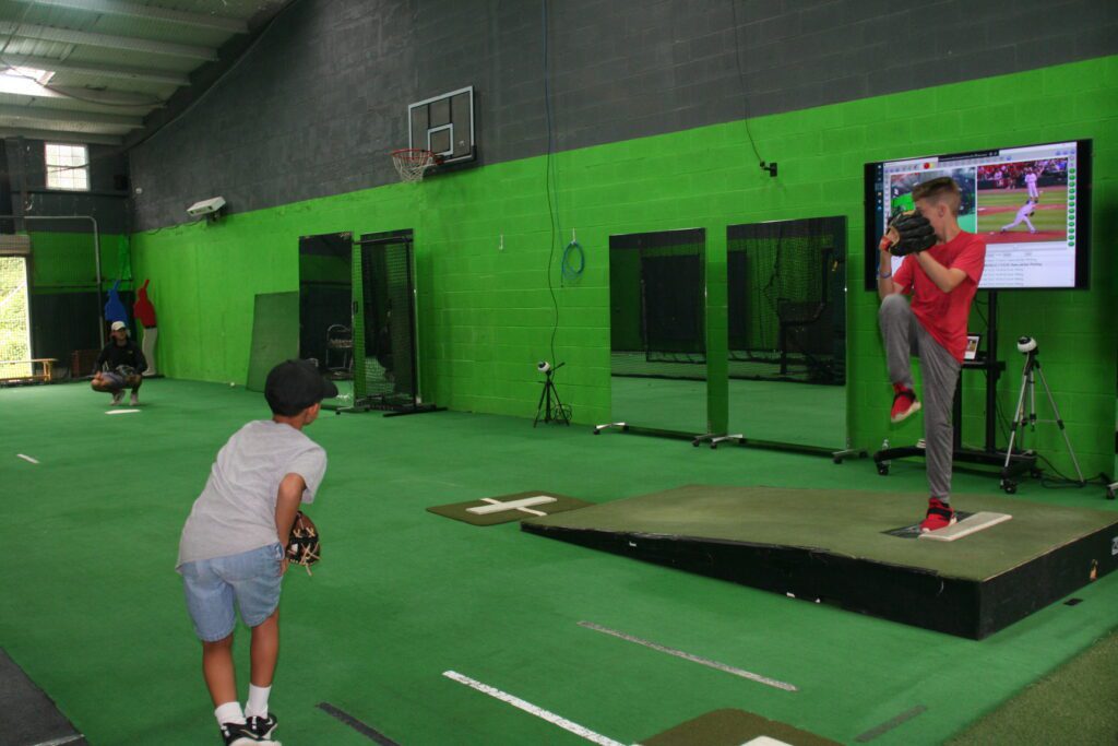 A man and boy playing baseball in an indoor facility.