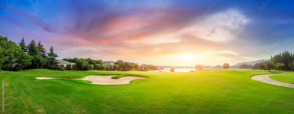 A golf course with sun setting in the background.