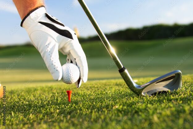A person holding a golf ball and putting on the green.